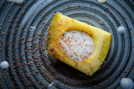 top view closeup original dessert of avocado half with white cream filling and chocolate shavings...