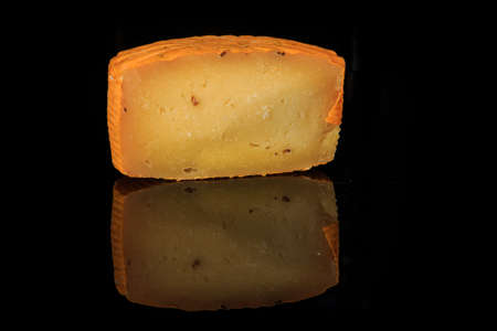 half of hard porous yellow gouda cheese head with holes on black mirror background with reflection and copy spaceの写真素材