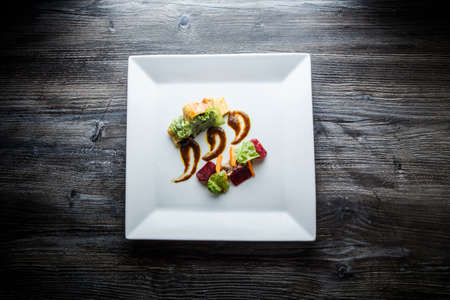 top view on original dish of baked in dough meat with mushrooms and spinach decorated with salad and sauce on white plate on wooden tableの写真素材
