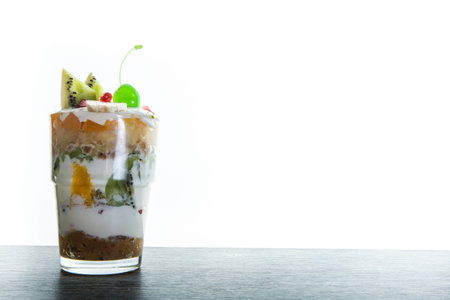 mousse cream and fruits dessert with sliced kiwi and green jelly cherry served in glass against white backgroundの写真素材