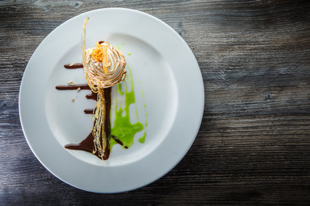 top view on delicious baked swan-shaped cream dessert with chocolate and caramel decoration on round restaurant plateの写真素材