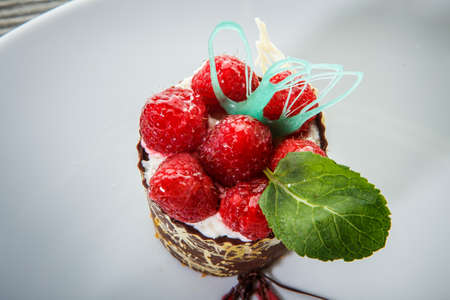 top view macro chocolate dessert with cream mousse filling and fresh raspberry decoration against white backgroundの写真素材