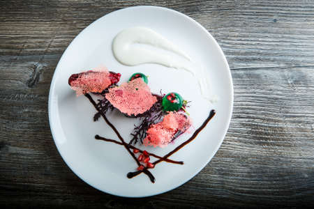 top view on originally decorated delicious restaurant dessert served on white plate on dark wooden table backgroundの写真素材