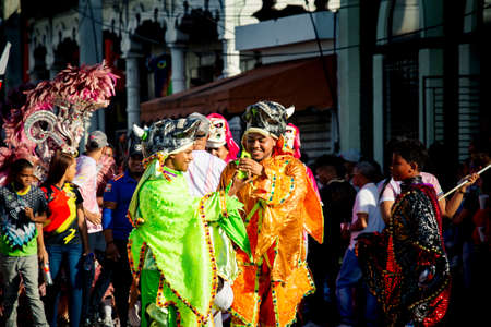 Concepcion De La Vega, DOMINICAN REPUBLIC - FEBRUARY 09, 2020: young men in motley costumes pass on city street at dominican annual carnival on February 9 in Concepcion De La Vegaのeditorial素材