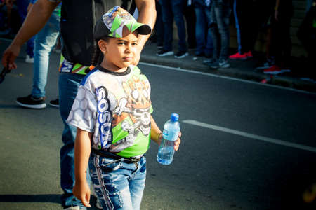 Concepcion De La Vega, DOMINICAN REPUBLIC - FEBRUARY 09, 2020: small girl in variegated costume passes by city street at dominican annual carnival on February 9 in Concepcion De La Vegaのeditorial素材