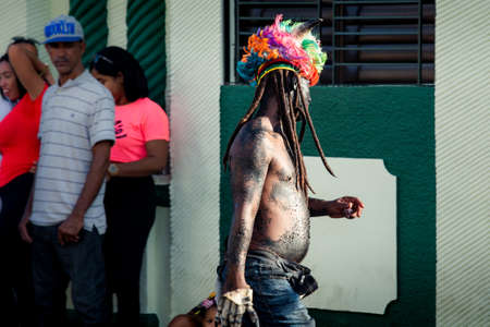 Concepcion De La Vega, DOMINICAN REPUBLIC - FEBRUARY 09, 2020: native man in strange costume walks by city street at dominican annual carnival on February 9 in Concepcion De La Vegaのeditorial素材