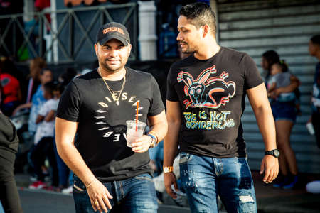 Concepcion De La Vega, DOMINICAN REPUBLIC - FEBRUARY 09, 2020: young native men in bright stylish clothes walk by city street at dominican carnival on February 9 in Concepcion De La Vegaのeditorial素材