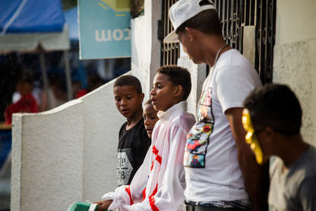 Concepcion De La Vega, DOMINICAN REPUBLIC - FEBRUARY 11, 2019: young boys in colorful costumes hide from rain on city street at dominican carnival on February 11 in Concepcion De La Vegaのeditorial素材