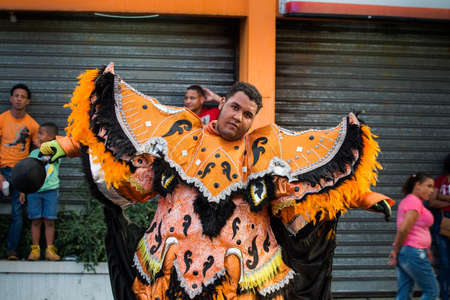 Concepcion De La Vega, DOMINICAN REPUBLIC - FEBRUARY 11, 2019: young man in bright costume poses for photo on city street at dominican carnival on February 11 in Concepcion De La Vegaのeditorial素材