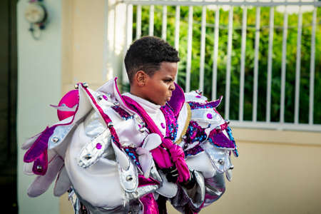 Concepcion De La Vega, DOMINICAN REPUBLIC - FEBRUARY 09, 2020: closeup small boy in glossy costume passes by city street at dominican carnival on February 9 in Concepcion De La Vegaのeditorial素材