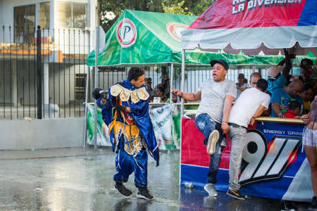 Concepcion De La Vega, DOMINICAN REPUBLIC - FEBRUARY 11, 2019: people in pied blue costumes having fun under tropical rain at dominican carnival on February 11 in Concepcion De La Vegaのeditorial素材