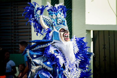 Concepcion De La Vega, DOMINICAN REPUBLIC - FEBRUARY 09, 2020: man in blue shiny masquerade costume pass by city street at dominican carnival on February 9 in Concepcion De La Vegaのeditorial素材