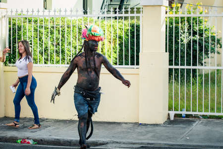 Concepcion De La Vega, DOMINICAN REPUBLIC - FEBRUARY 09, 2020: big man in strange devil costume passes by city street at dominican annual carnival on February 9 in Concepcion De La Vegaのeditorial素材