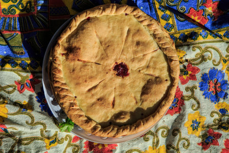 top view on golden whole round raspberry pie decorated with braided border