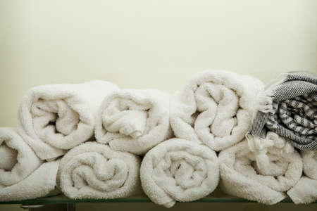 many small twisted white and gray towels served on glass shelf against creamy wall backgroundの写真素材