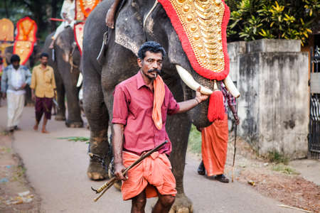 Kottayam, Kerala, INDIA - JANUARY 25, 2012: closeup indian men and elephants walking by village street on traditional festival on January 25 in Kottayamのeditorial素材