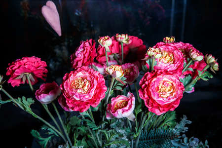 beautiful elegant bouquet made from large artificial red peonies and assorted greenery served against dark backgroundの写真素材