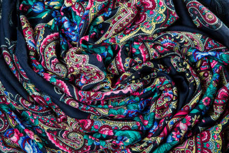 top view closeup folded dark soft cotton scarf with bright red, blue and green floral printの写真素材