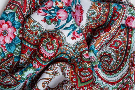 horizontal view closeup on crumpled white cotton female scarf with colorful paisley and floral ornament with bright colorsの写真素材