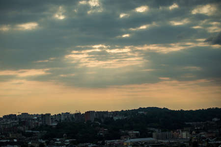 beautiful sunset with heavy gray clouds on dramatic dark sky above large cityscape silhouettesの写真素材