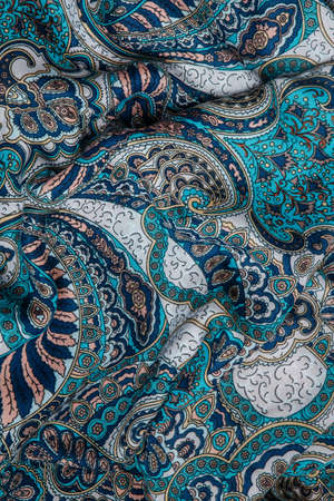 top view closeup on crumpled soft cotton scarf with bright oriental ornament with blue, green and yellow colorsの写真素材