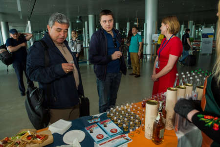 LVIV, UKRAINE - MAY 24, 2018: different passengers try snacks and drinks from free degustation table in Lviv airport hall on May 24 in Lvivのeditorial素材
