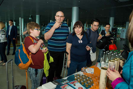 LVIV, UKRAINE - MAY 24, 2018: different passengers try drinks from free degustation table in Lviv airport hall on May 24 in Lvivのeditorial素材
