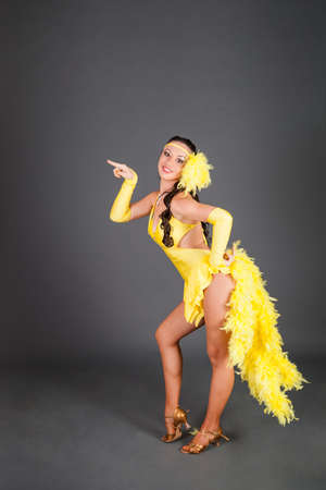 beautiful brunette caucasian model with curly hair in frank yellow suit dances against gray background in studioの写真素材