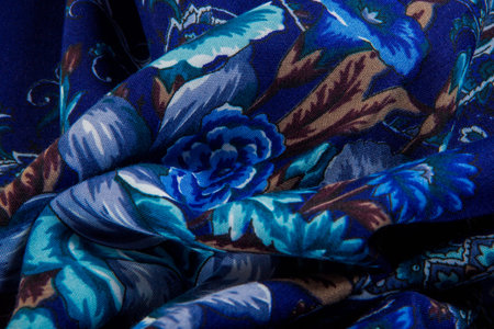 top view macro part of folded textured bright blue paisley and floral rose pattern on dark blue...