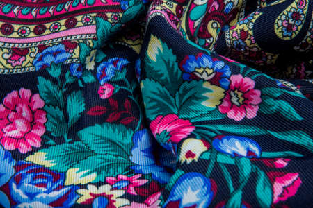 top view closeup textured dark folded soft cotton scarf with bright red, blue and green floral printの写真素材