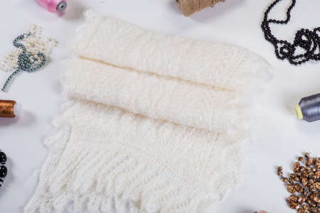 top view folded handmade white woolen scarf with knitted pattern designed with beauty accessories on light gray backgroundの写真素材