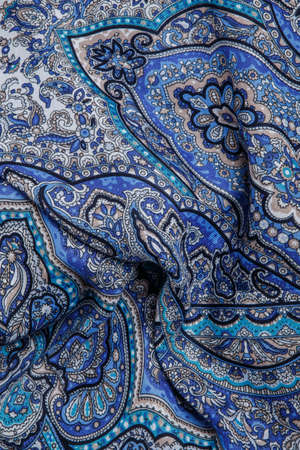 top view closeup on crumpled soft blue cotton scarf with bright oriental paisley ornament with blue, beige and black colorsの写真素材