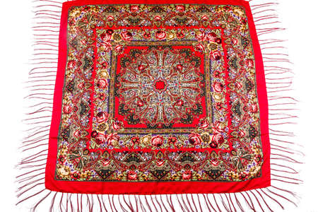 flat lay top view on red cotton scarf with fringe and bright floral roses ornament with red, brown and yellow colors lay on white backgroundの写真素材