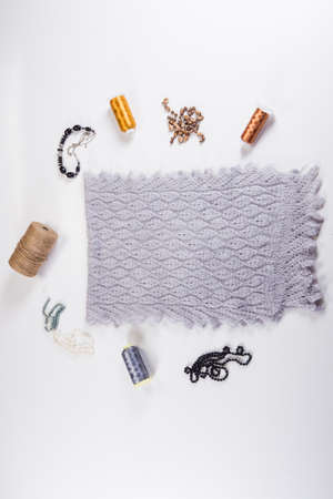 top view on folded handmade gray woolen scarf with knitted pattern designed with different beauty accessories on white backgroundの写真素材
