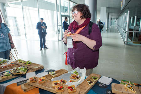 many passengers try snacks and drinks from free degustation table in Lviv airport hallのeditorial素材