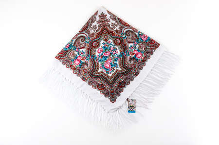top view on flat white cotton scarf with fringe and bright floral ornament with pink, brown and blue colors lay on white backgroundの写真素材