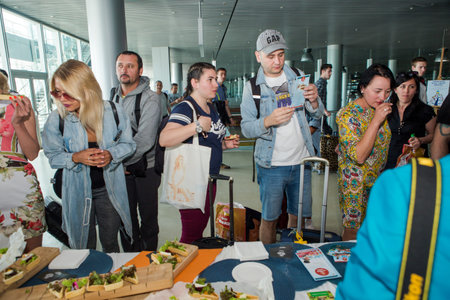 LVIV, UKRAINE - MAY 24, 2018: different passengers try snacks and drinks from free degustation table...