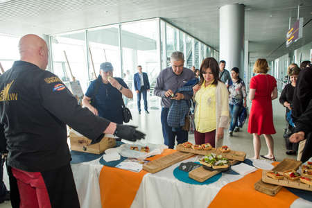 many passengers try snacks and drinks from free degustation table in Lviv airport hallのeditorial素材