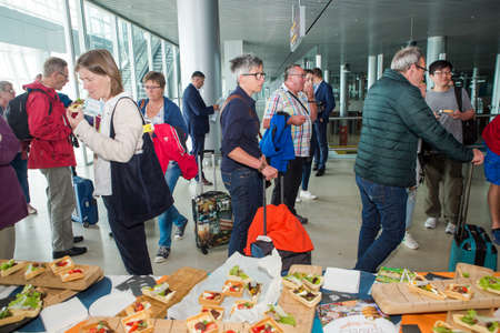 many passengers try snacks and drinks from free degustation table in Lviv airport hallのeditorial素材