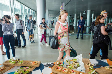 different passengers try snacks and drinks from free degustation table in Lviv airport hallのeditorial素材
