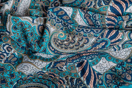 top view closeup on crumpled blue soft cotton scarf with bright oriental ornamentの写真素材