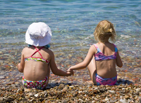 Two girls sitting on the shore of sea  の写真素材