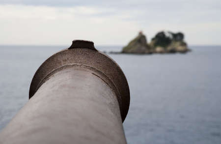 Old fashioned sea cannon aimed at island   の写真素材