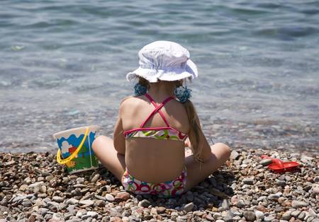 Little girl sitting on the shore of sea  の写真素材