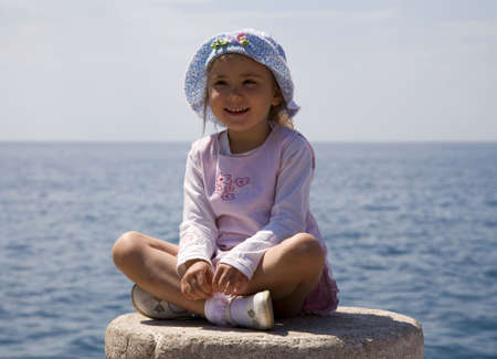 Little girl sitting on the sea bollardの写真素材