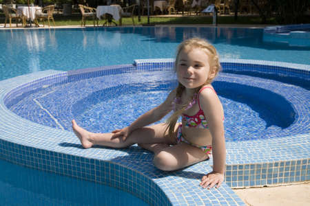 Little girl sitting near swimming pool  の写真素材