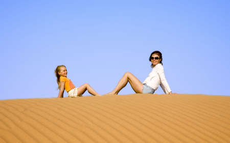 Mother with daughter sitting on the dune  の写真素材