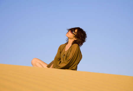 Pretty woman sitting on the dune  の写真素材