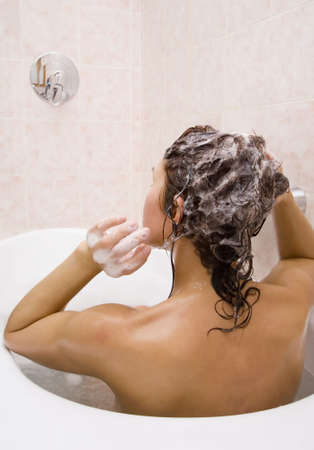 Young woman takes a bath with shampoo  の写真素材