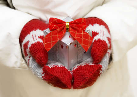 Hands in the red mitten giving Christmas gift の写真素材